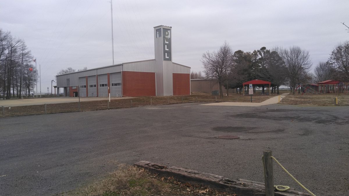 Dell fire department building on the left with empty parking lot on the right.