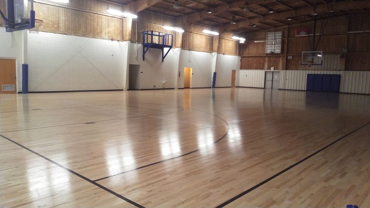 Picture of Dell Gym's basketball court with half the lights on.