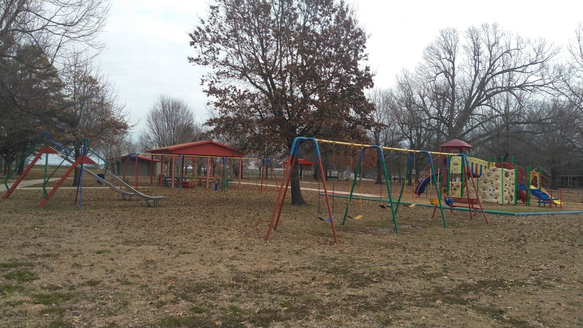 A pair of slides, large swing set, and a large piece of playground playset equipment 