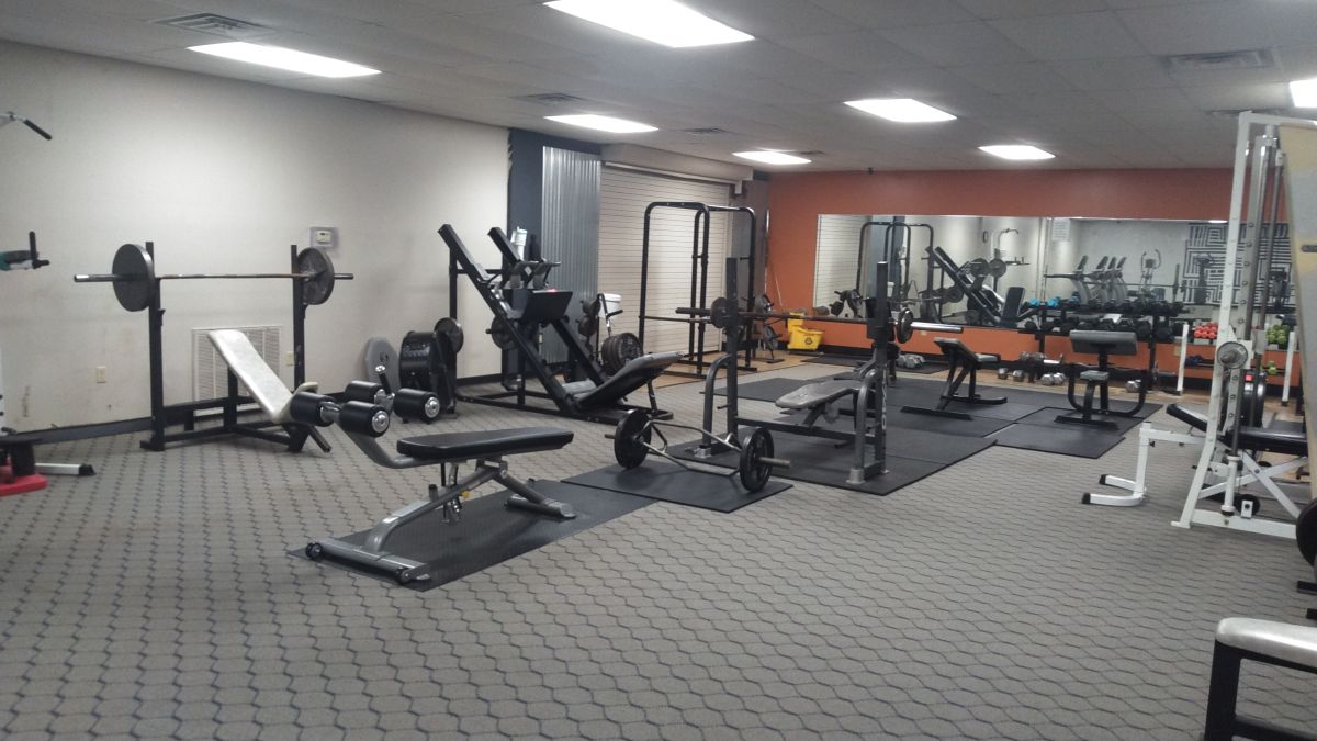 9 sets of weight lifting equipment with a mirror and weight rack in the back at Dell Gym's Weight Room