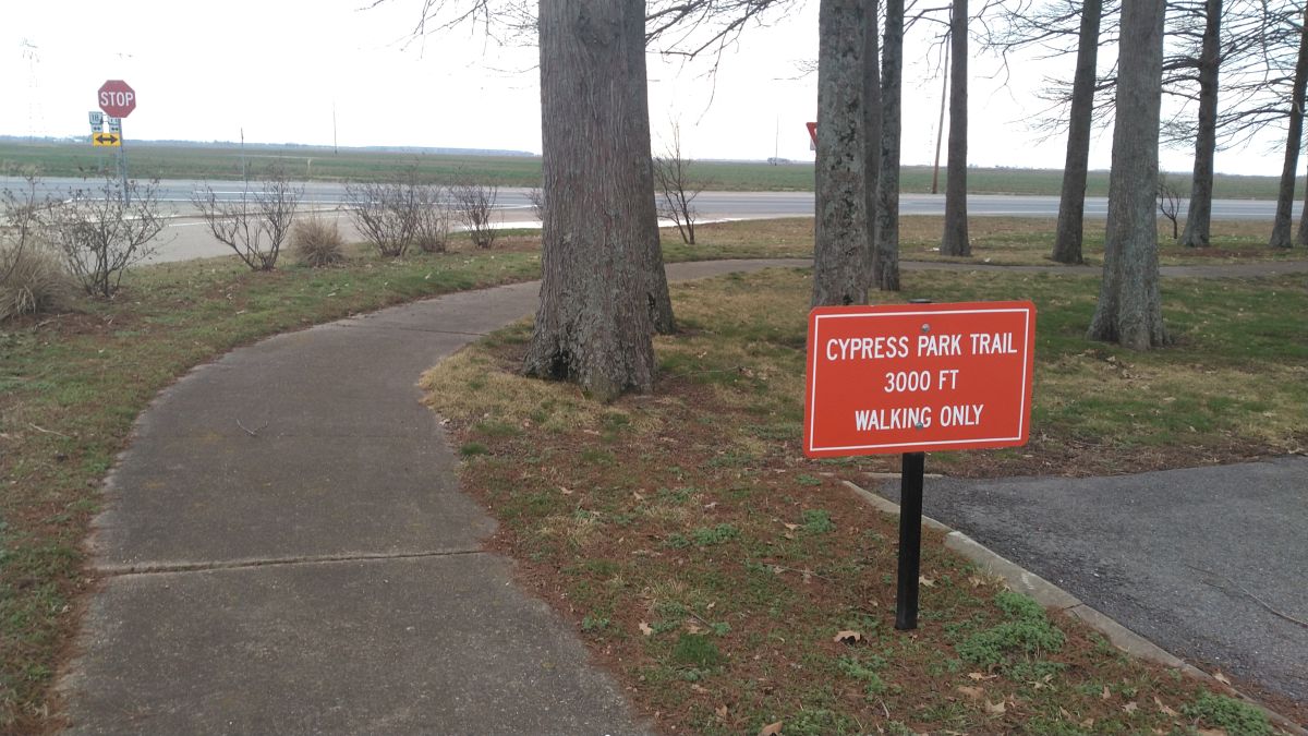 One of the entrances to the Cypress Park Trail with a red sign at center-right that says, "Cypress Park Trail, 3000 FT, Walking Only."